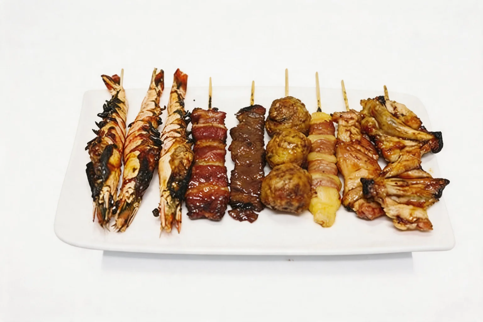 Neuf brochettes grillées variées — crevettes, bœuf, boulettes, fromage et poulet — sur une assiette blanche